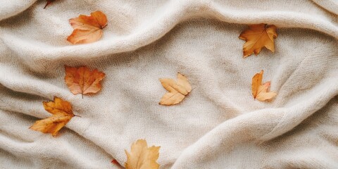 Autumn leaves scattered on a beige knitted blanket