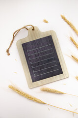 Blank small chalkboard and ears of wheat on a light beige background. View from above. Menu, receipe template.