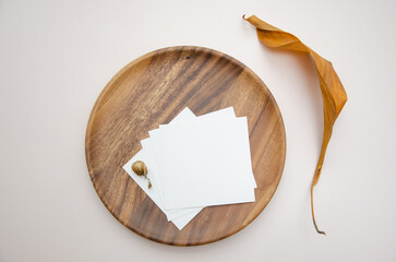Blank white business card mockup on wooden plate. Beige backgound with dry hop cones. Modern template. Branding identity. Natural autumn, fall design. Flat lay, top view.