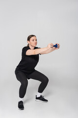 Female athlete demonstrating a squat exercise indoors for fitness and strength training