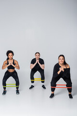 Fototapeta premium Fitness enthusiasts strengthening their legs with resistance bands in a modern indoor studio