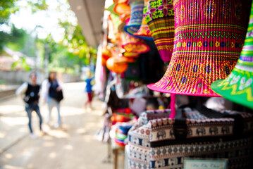 Obraz premium Motion blurred customers visiting souvenir shop variety of brocade embroidered silk colorful lanterns, traditional Thai ethnic dress, handmade decorative craft stilt house, Mai Chau, Hoa Binh