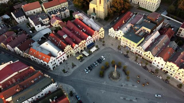 An aerial view of the charming architecture of a small Czech town, captured by a drone. The scene showcases traditional buildings, cobblestone streets, and historic landmarks, highlighting the town's 