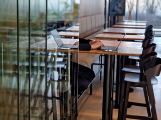 behind a glass partition that is foldable and sliding on rails. a businesswoman is sitting with a...