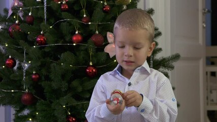 Happy child holding snow globe with figurine of Santa Claus. Smiling face of little boy near Christmas tree. Merry Christmas and Happy New year winter holidays.