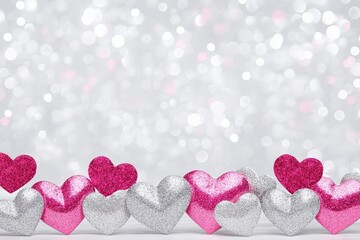 Fototapeta premium Glittering Hearts Valentine's Day Background - Pink and silver glitter hearts against a sparkling silver background. Perfect for Valentine's Day cards, websites, or social media.