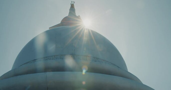 Sun shining above Japanese Peace Temple In Rumassala, Galle, Sri Lanka. Famous landmark and cultural sacred place. View of the Japanese built Buddhist Temple Peace Pagoda at Roomasala Hill overlooking