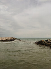 Fototapeta premium Waves crashing against breakwaters on a cloudy day in bibione, italy, creating a yet dynamic scene