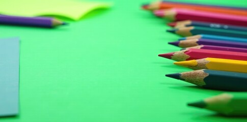 Obraz premium Green paper scattered on a table with colored pencils in a neat row, purple, pencils, desk