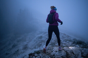 Determined Woman Trail Running at Night, Illuminated by a Headlamp in the Mountain Wilderness.
