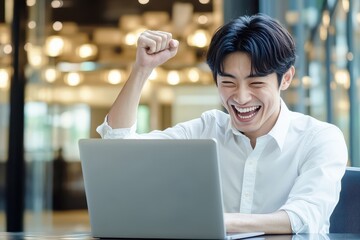 パソコンの前でガッツポーズをする笑顔の男性会社員（達成感・プレゼン・勝利・嬉しい・喜ぶ）