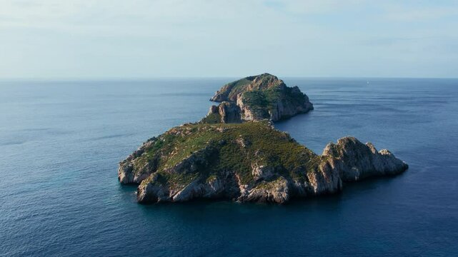 Aerial drone flyover footage of rock formations and cliffs of Islas Malgrats, Santa Ponca in Mallorca, Spain. Serene Mediterranean Sea, seagulls fly. Tourist sailing destination for summer holiday