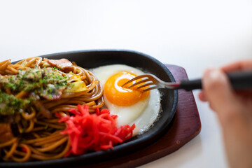 焼きそばの目玉焼きをフォークで刺す