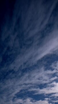 A timelapse captures clouds drifting under a dark blue sky. Steady motion, evoking peace.
