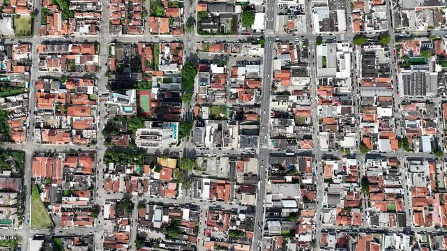 Vis&atilde;o a&eacute;rea de v&aacute;rios quarteir&otilde;es de casas com telhados. Imagem panor&acirc;mica destacando a organiza&ccedil;&atilde;o e arquitetura das resid&ecirc;ncias, oferecendo uma perspectiva do ambiente urbano