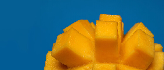 Cubes of fresh mango close-up on a blue background with copy space, vibrant tropical fruit...