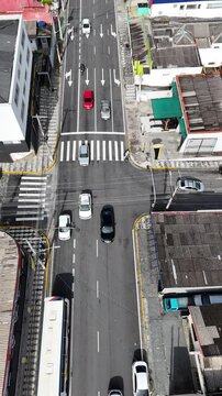 V&iacute;deo vertical mostrando o tr&aacute;fego de ve&iacute;culos em um cruzamento movimentado em Mogi das Cruzes, SP, com destaque para a movimenta&ccedil;&atilde;o intensa no tr&acirc;nsito e os sinais de tr&acirc;nsito