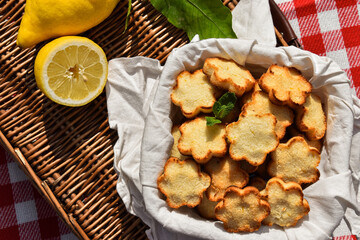 Homemade lemon and coconut crunchy cookies made for a picnic/lunch. Served on a picnic basket with fresh lemons.