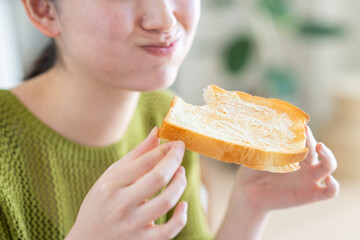 朝食で食パンを食べる若い女性