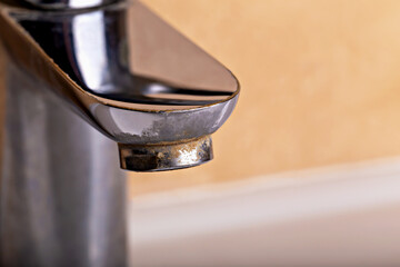 Chrome faucet with visible limescale buildup on spout, highlighting need for cleaning and...