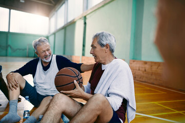 Senior men laughing after playing basketball indoors