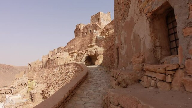Walking past homes and other buildings in beautiful Berber village of Chenini, built on a mountain ridge in Southern Tunisia
