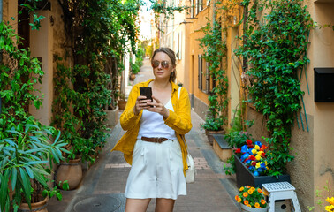 Female tourist with smartphone walks through the old city.