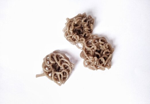 Three raw brown curly cracker doughs (kerupuk mie mentah) isolated on a plain white background.