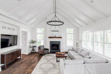 A modern farmhouse living room with shiplap, exposed white beams, a fireplace, and furniture on...