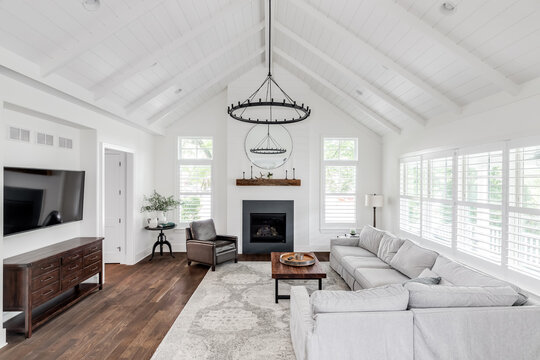 A modern farmhouse living room with shiplap, exposed white beams, a fireplace, and furniture on hardwood floors. No brands or labels.