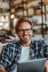 Fototapeta premium Smiling Young Man with Glasses Relaxed on Couch, Browsing Laptop, Enjoying Leisure Time at Home,