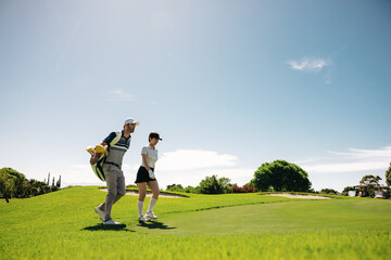 Female golf player walking with golf gear on the fairway