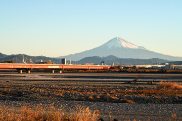 川越しに望む朝日に照らされた富士山