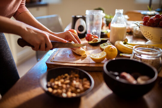Close up of a woman chopping banana for a smoothie with fresh ingredients