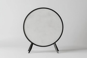 Fototapeta premium Stylish Round Mirror with Sleek Black Frame on Tripod Stand