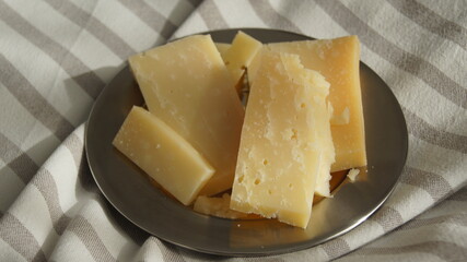 Hard cheese Malga extra aged, cheese from cow's milk alpine, yellow cheese cut into pieces, on a white tablecloth, Italy