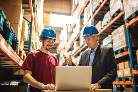Warehouse manager and worker discussing logistics in storage facility