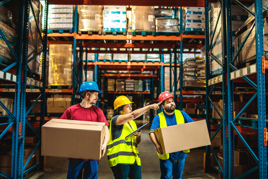 Warehouse workers carrying boxes while supervisor giving instructions in storage facility