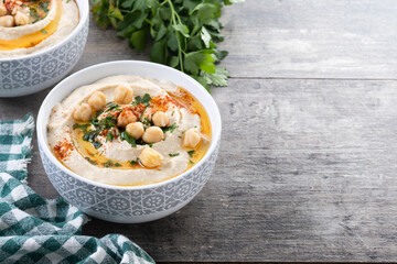 Chickpea hummus with olive oil, parsley and paprika in bowl on wooden table. Copy space