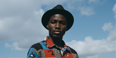 A confident young African American man radiates pride, wearing a stylish hat that frames his charismatic and determined expression
