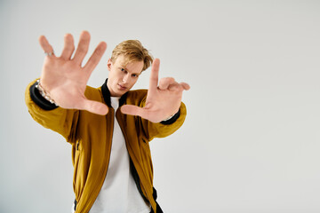 Captivating young man expresses energy in a stylish outfit against a minimalist backdrop