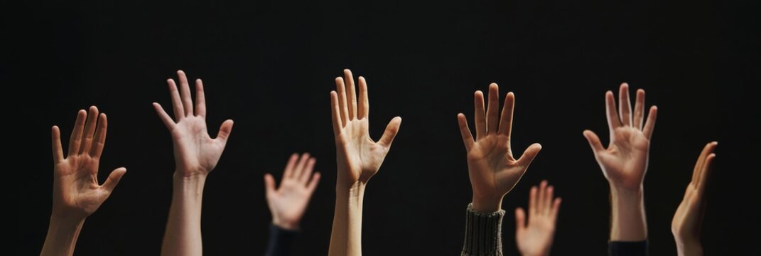 Numerous hands are raised against a striking black background, indicating a strong desire for participation and eagerness to actively engage in a meaningful discussion during a vibrant event