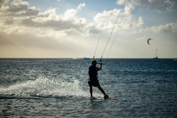 Enthusiastic Kiteboarder Navigating Waves Against a Dramatic Ocean Sunset with Skill and Precision