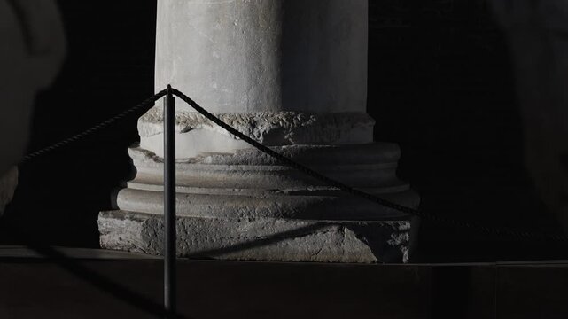 A pillar with a black rope around it. The pillar is made of stone