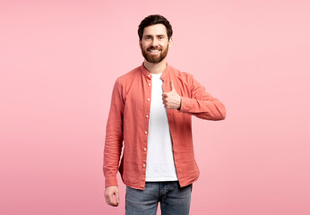 Cheerful young bearded man in casual showing thumb-up and smiling, isolated