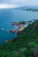 Scenic coastal view of South Africa featuring rocky shores and lush greenery on a cloudy day