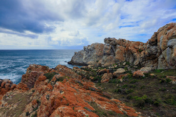 Rocky coastal landscape in South Africa with ocean waves under cloudy sky
