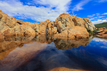 Tranquil rock formations reflecting in a serene water pool during a bright day in South Africa