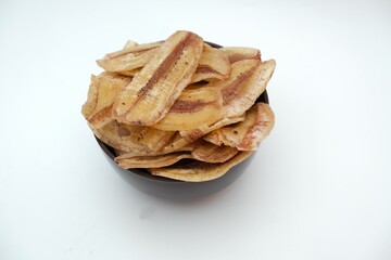 Fried banana slices or banana chips, on black bowl, isolated on white background