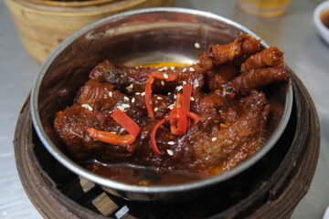 Steamed Chicken Feet with Black Bean Sauce served in bamboo steamer on table